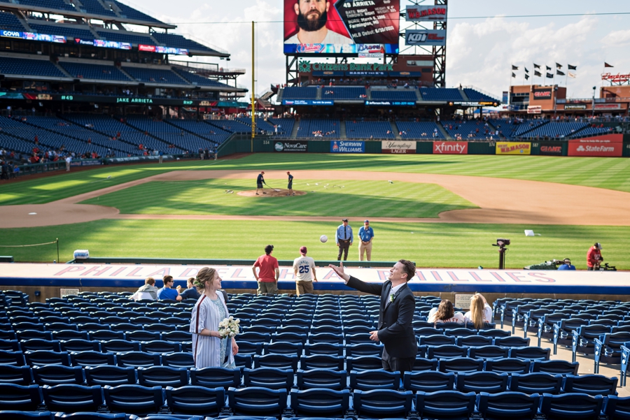 A bride and groom play catch with a baseball at a Phillies game before their reception starts.